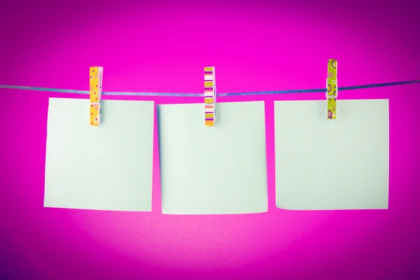 Leere Papierbögen auf einer Wäscheleine vor rotem Hintergrund — Stockfoto