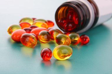 Red and yellow capsules of vitamins on a blue background