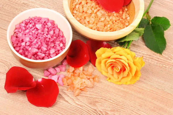 Aromatische badzout, rose en bloemblaadjes op houten achtergrond — Stockfoto