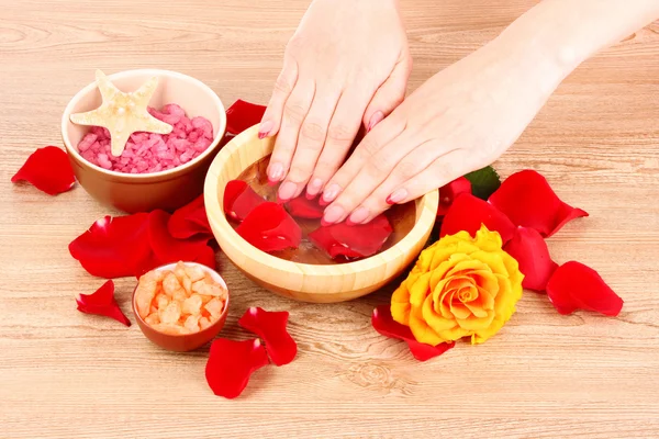 Handen in water met rozenblaadjes — Stockfoto