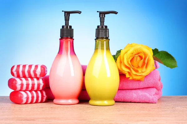 Розовые полотенца, мыло и желтая роза на голубом — стоковое фото