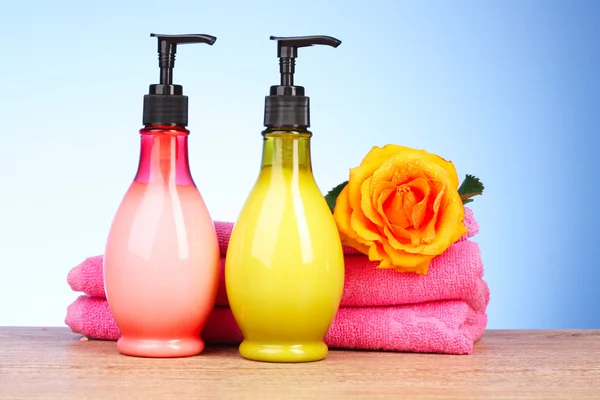 Roze handdoeken, zeep bar en gele roos op blauw — Stockfoto