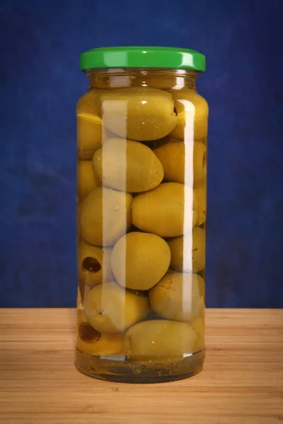 Inlagda oliver i glasburk på blå — Stockfoto