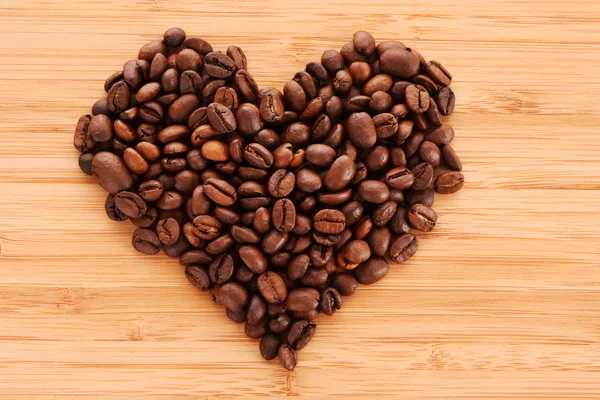 Grains de café en forme de coeur sur fond brun — Photo