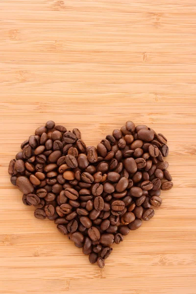 Szemes kávé a szív alakú barna háttér — Stock Fotó