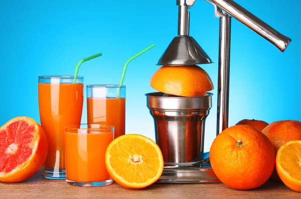 Juicer e laranjas sobre fundo azul — Fotografia de Stock