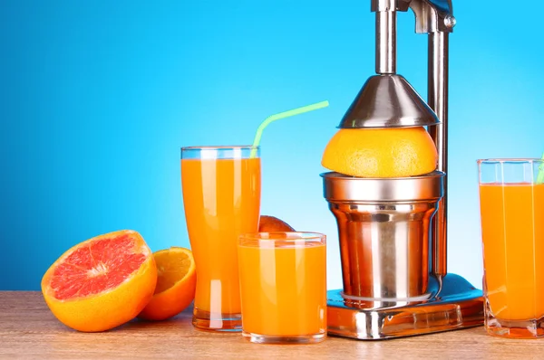 Exprimidor y naranjas sobre fondo azul — Foto de Stock