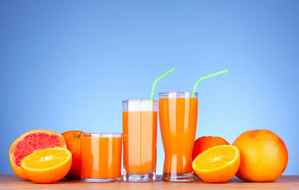 Juice och apelsiner på blå bakgrund — Stockfoto