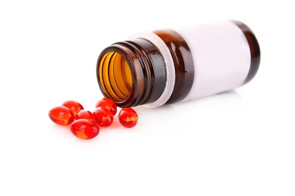 Rojos cápsulas de vitaminas sobre un fondo blanco — Stok fotoğraf
