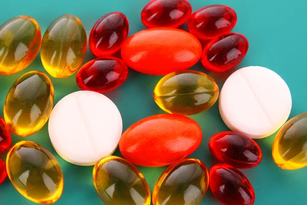 Červené a žluté kapsle vitamínů na modrém pozadí — Stock fotografie