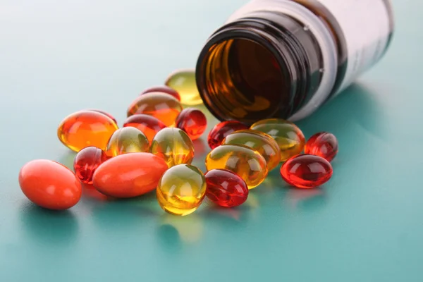 Cápsulas rojas de vitaminas sobre un fondo azul — Foto de Stock
