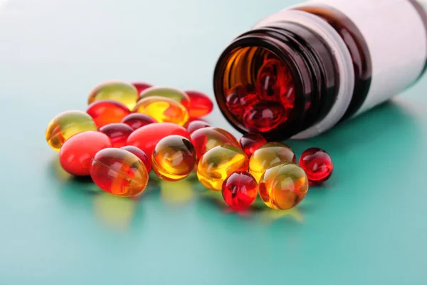 Cápsulas rojas de vitaminas sobre un fondo azul — Foto de Stock