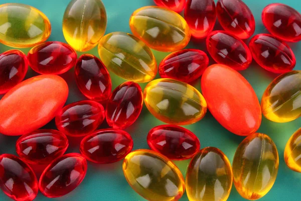 Cápsulas rojas y amarillas de vitaminas sobre un fondo azul — Foto de Stock