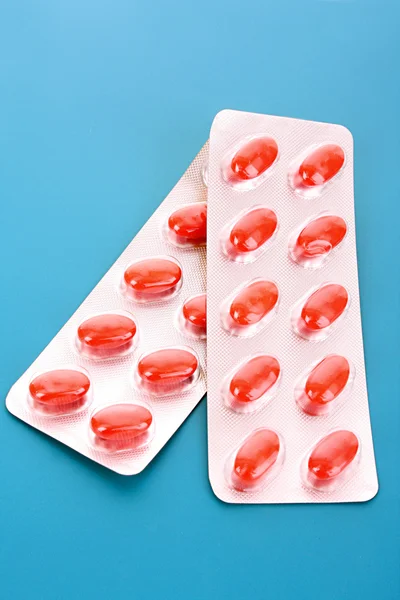 Vitamin mavi bir arka plan üzerinde kırmızı kapsül — Stok fotoğraf