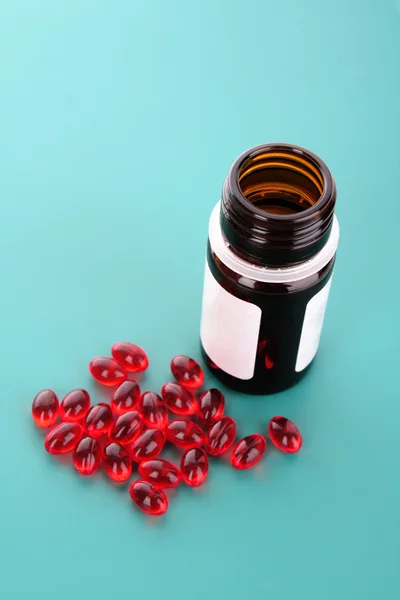 Cápsulas rojas de vitaminas sobre un fondo azul —  Fotos de Stock