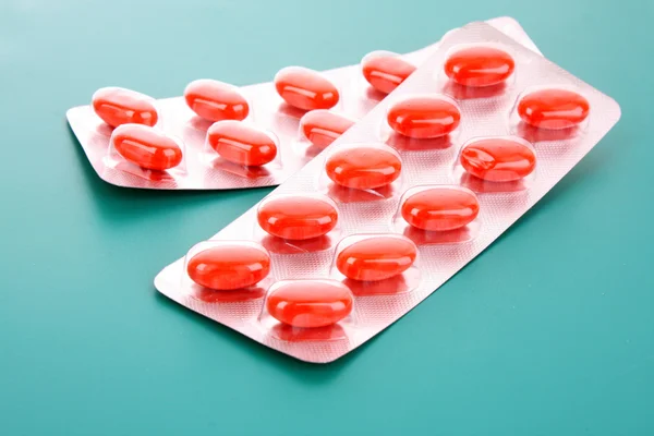 Capsule rosse di vitamine su sfondo blu — Foto Stock