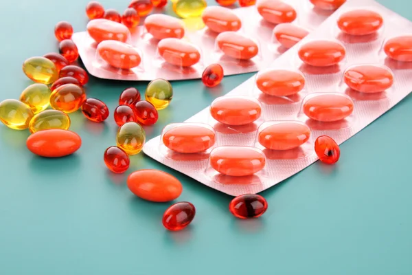 Cápsulas rojas de vitaminas sobre un fondo azul —  Fotos de Stock