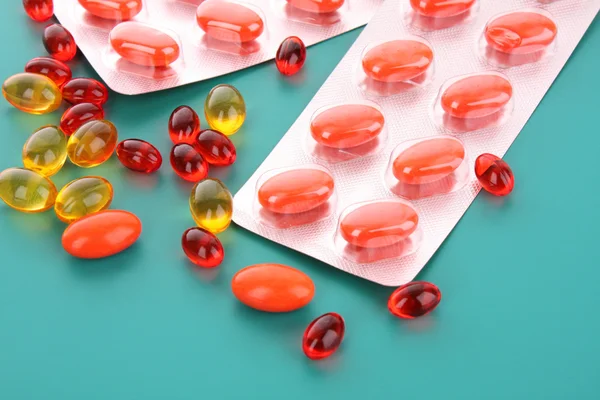 Cápsulas vermelhas de vitaminas em um fundo azul — Fotografia de Stock