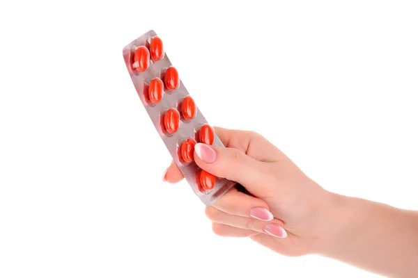 Cápsulas vermelhas de vitaminas na mão sobre um fundo branco — Fotografia de Stock