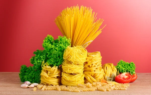 Vermicelli, Salat und Öl auf rotem Hintergrund — Stockfoto