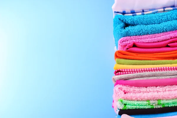 stock image Pile of colorful clothes over blue background