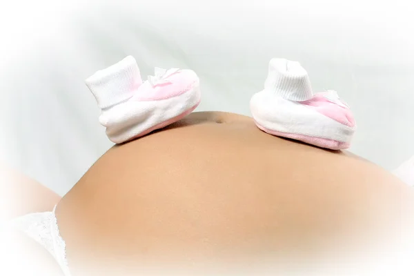 Baby booties on the belly pregnant mom — Stock Photo, Image