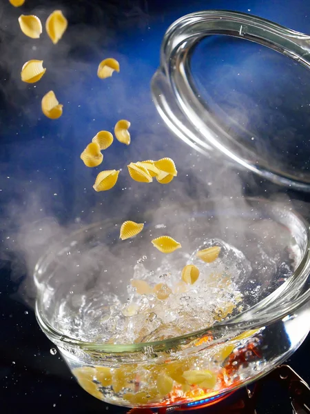 Makkaroni fallen in einen transparenten Topf mit kochendem Wasser Stockbild