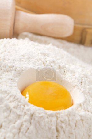 jaune d'oeuf dans la farine, rouleau à pâtisserie ang tamis sur fond 