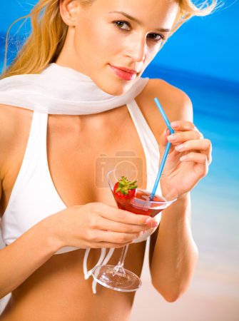 Jeune belle femme blonde avec cocktail sur la plage de la mer tropicale 