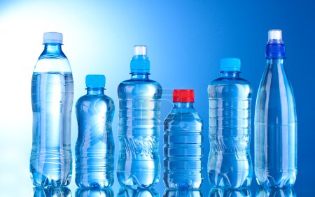 Groupe bouteilles d'eau en plastique sur fond bleu 
