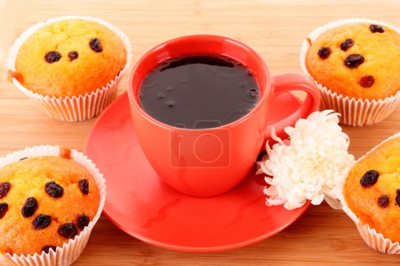 Muffins avec raisins secs et tasse rouge sur la surface en bois 